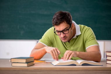 Sınıfta tahtaya oturan genç bir öğrenci.