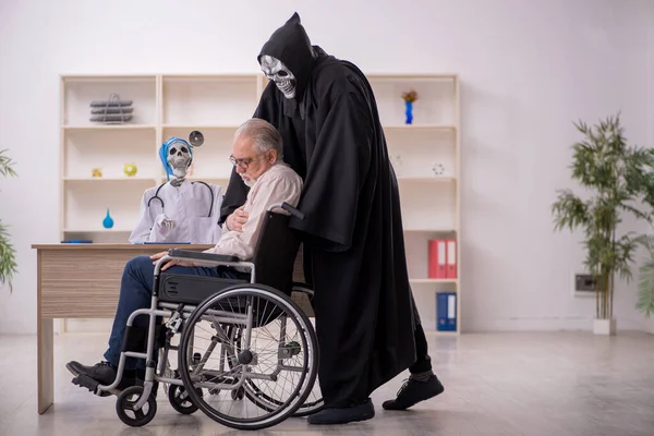 Old male patient in wheel-chair visiting two devil doctors