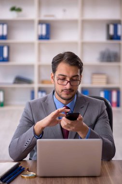 Genç işadamı işyerinde oturuyor.