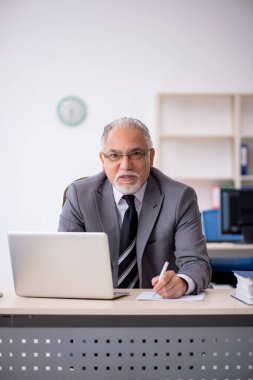 İş yerinde oturan yaşlı erkek çalışan.