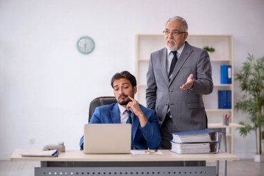 Eski patron ve genç çalışan işyerinde çalışıyor.