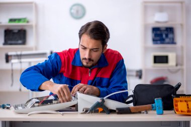 Genç tamirci atölyede ısıtıcıyı tamir ediyor.