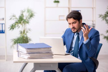 Genç bir çalışan ve ofiste çok fazla iş var.