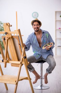 Genç adam evde resim yapmaktan hoşlanıyor.