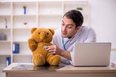 Genç doktor oyuncak ayı tutuyor.