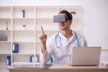 Genç erkek doktor klinikte sanal gözlüklerin keyfini çıkarıyor.