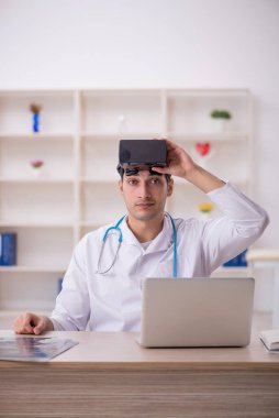 Genç erkek doktor klinikte sanal gözlüklerin keyfini çıkarıyor.