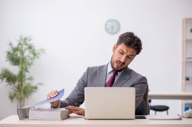 Genç işadamı işyerinde oturuyor.