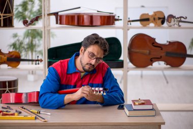 İçeride müzik aletlerini tamir eden genç bir adam.
