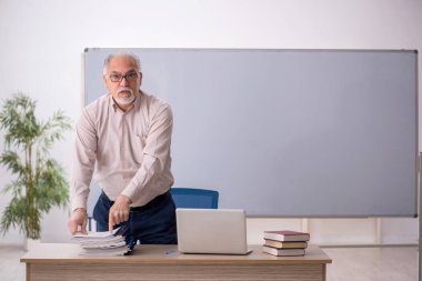 Eski öğretmen beyaz tahtanın önünde.