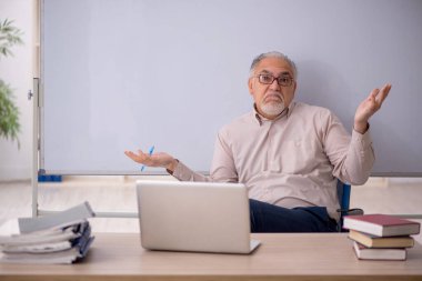Eski öğretmen beyaz tahtanın önünde.