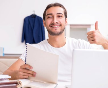 Genç erkek öğrenci evde sınavlara hazırlanıyor.