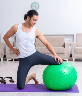 Genç adam evde antrenman ve egzersiz yapıyor.