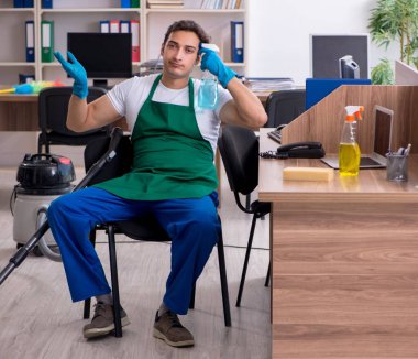 Genç yakışıklı müteahhit ofisi temizliyor.