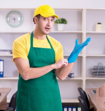 Genç erkek müteahhit ofisi temizliyor.