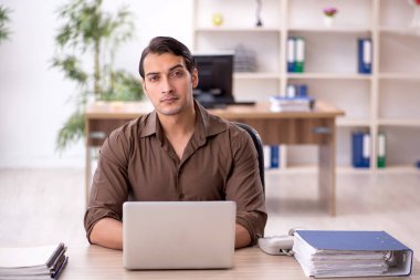 Genç erkek çalışan işyerinde oturuyor.