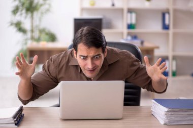 Genç erkek çalışan işyerinde oturuyor.