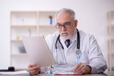 Klinikte çalışan yaşlı bir doktor.