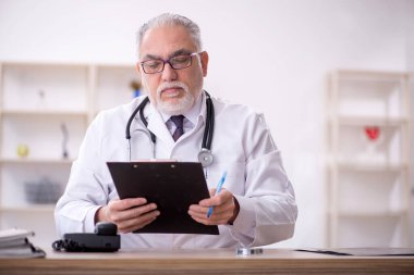 Klinikte çalışan yaşlı bir doktor.