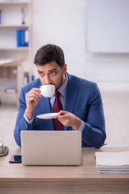 İş yerinde kahve içen genç bir çalışan.