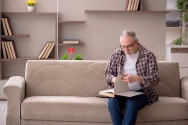 Old man reading book at home during pandemic