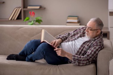 Old man reading book at home during pandemic