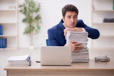 Genç işadamı ve işyerinde çok fazla iş var.