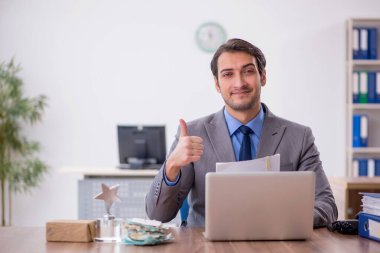 Genç işadamı işyerinde oturuyor.