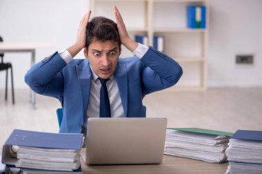 Genç işadamı ve işyerinde çok fazla iş var.