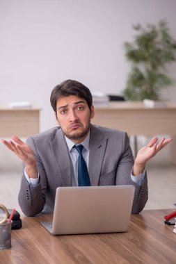 Genç erkek çalışan işyerinde oturuyor.