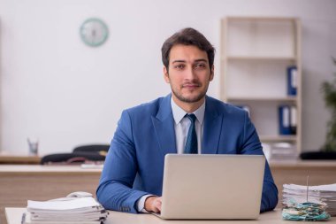 Genç erkek çalışan işyerinde oturuyor.