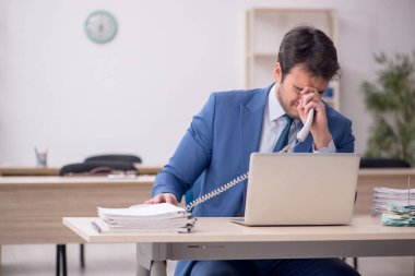 Genç erkek çalışan işyerinde oturuyor.