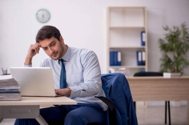 Genç erkek çalışan işyerinde oturuyor.