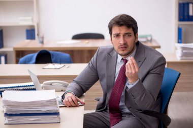 Genç erkek çalışan işyerinde oturuyor.