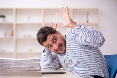 Genç erkek çalışan işyerinde oturuyor.