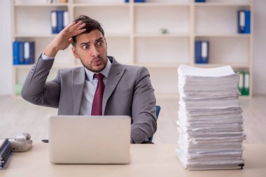 Young employee and too much work at workplace