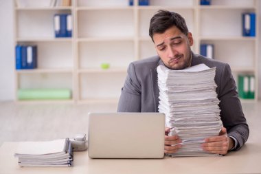 Young employee and too much work at workplace