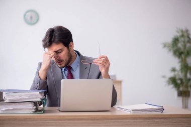 Young employee unhappy with excessive work at workplace