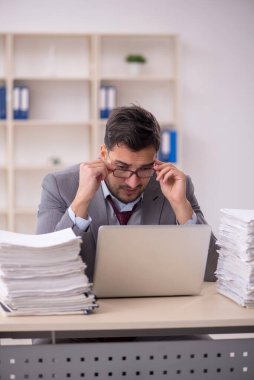 Young employee and too much work at workplace