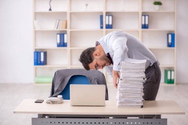 Young employee and too much work at workplace