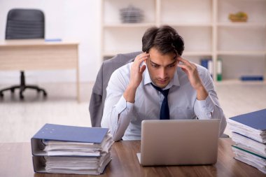Genç işadamı ve işyerinde çok fazla iş var.