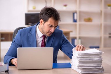 Genç işadamı ve işyerinde çok fazla iş var.