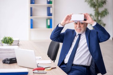 Old businessman employee wearing virtual glasses in the office