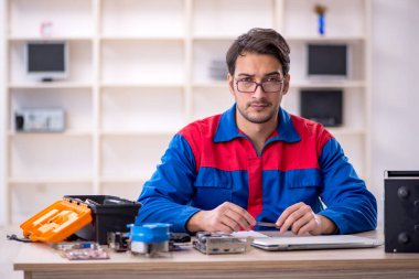 Atölyede bilgisayar tamir eden genç bir tamirci.