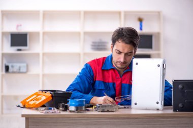 Atölyede bilgisayar tamir eden genç bir tamirci.