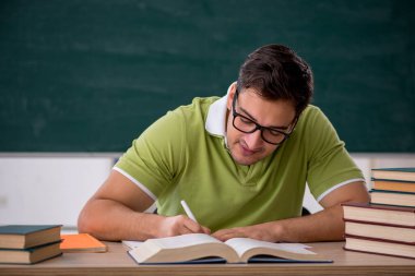 Sınıfta tahtaya oturan genç bir öğrenci.