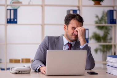 Genç işadamı işyerinde oturuyor.