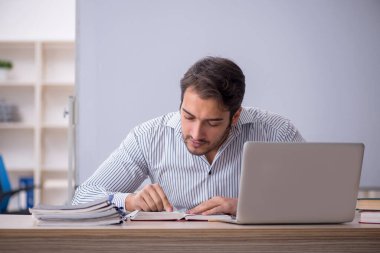 Genç öğretmen sınıfta oturuyor.