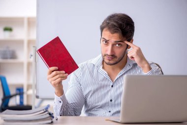 Genç öğretmen sınıfta oturuyor.