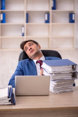 Genç işadamı ve işyerinde çok fazla iş var.